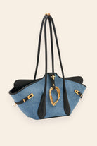 Blue handbag with black accents and gold hardware on a beige background